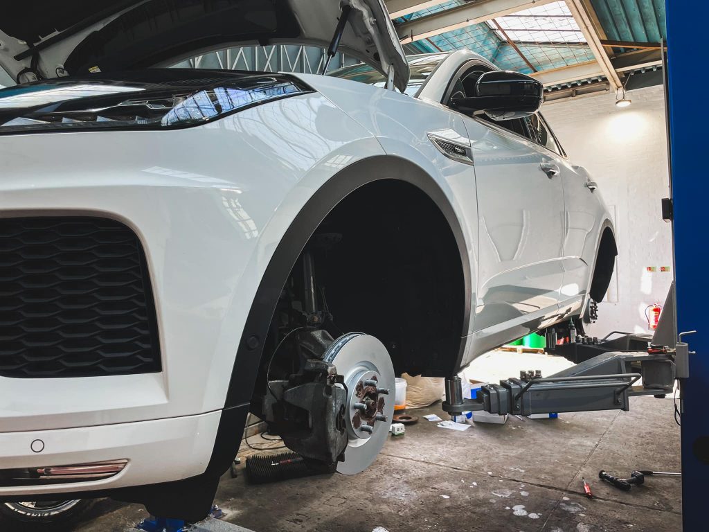 Repairs page image: A white jaguar 4x4 up on the jacks with its wheels off in the ASM Independent garage. ASM Independent: Independent Jaguar and Land Rover Specialists Wakefield.