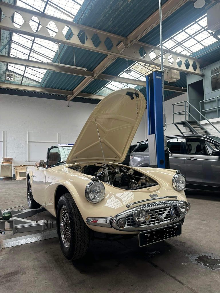 A cream coloured vintage Daimler in the garage with its bonnet open. ASM Independent: Independent Jaguar and Land Rover Specialists Wakefield.